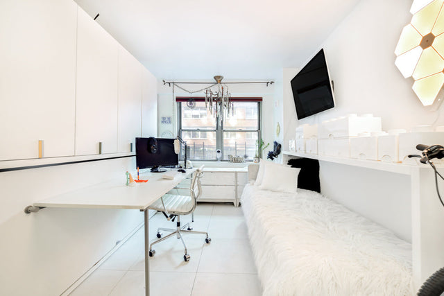 A bright, minimalist room with a large desk and a Kali wall bed unit, offering a streamlined, multifunctional space for work and rest.