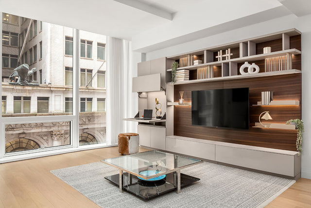 Wall-mounted shelving and flip-down desk with hidden storage in an NYC studio at One Wall Street.