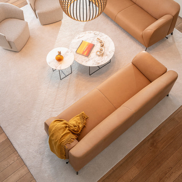 Overhead view of caramel leather Como sofas with round nesting tables and sculptural lighting