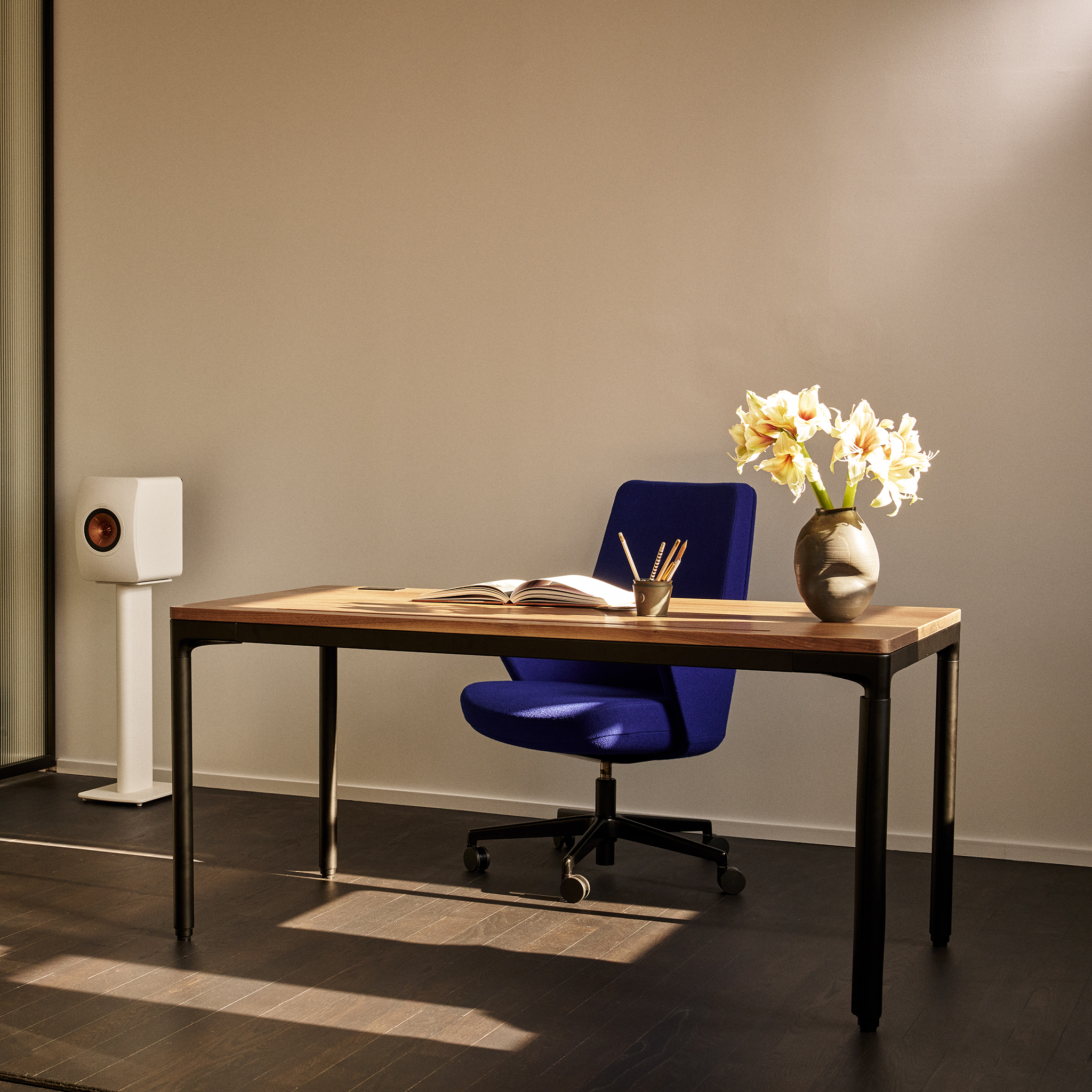 eFloat Quattro in a soft-lit home office setting, styled with flowers and a bright blue task chair.