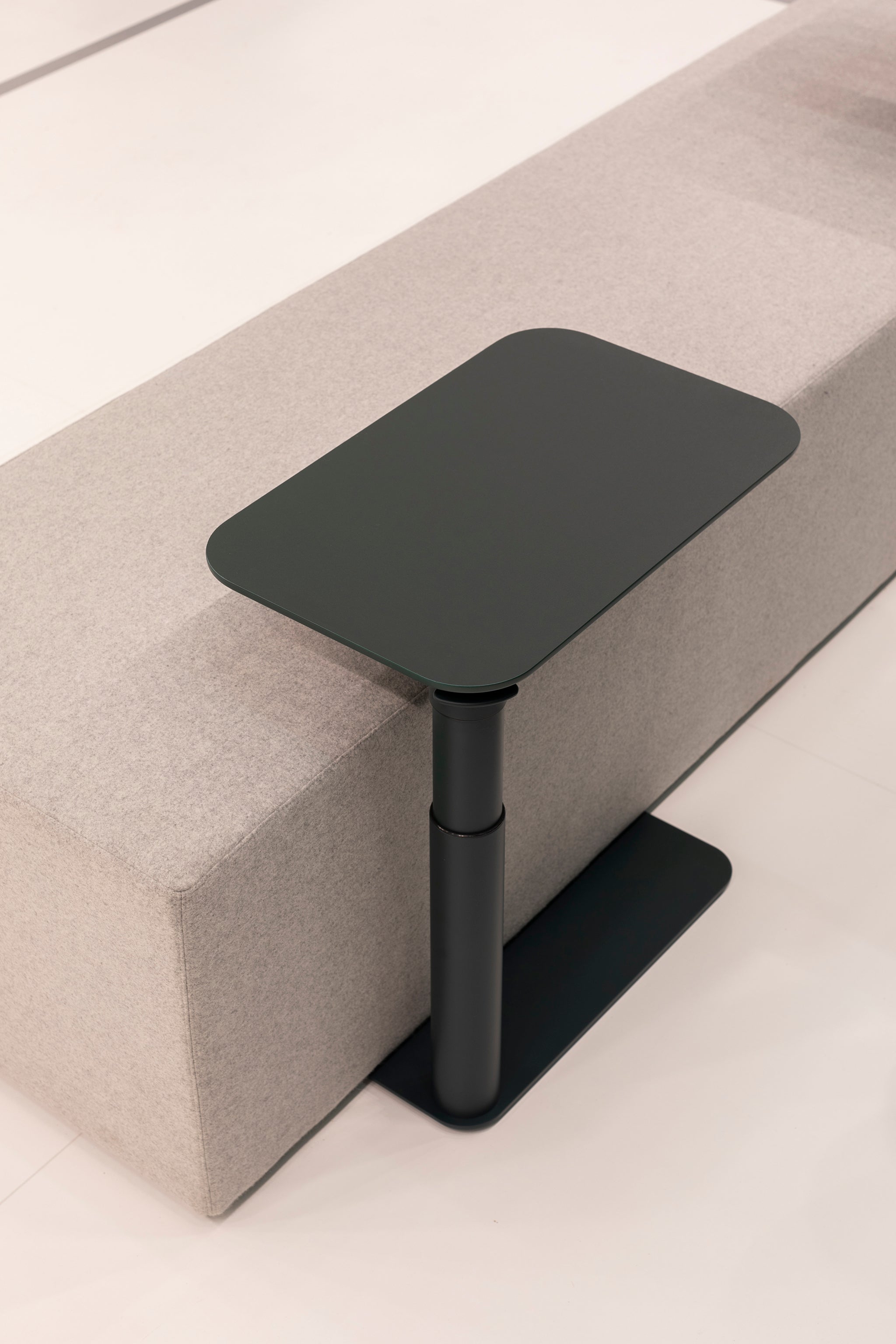 Close-up of black Float Micro table integrated into a showroom installation with wall backing.