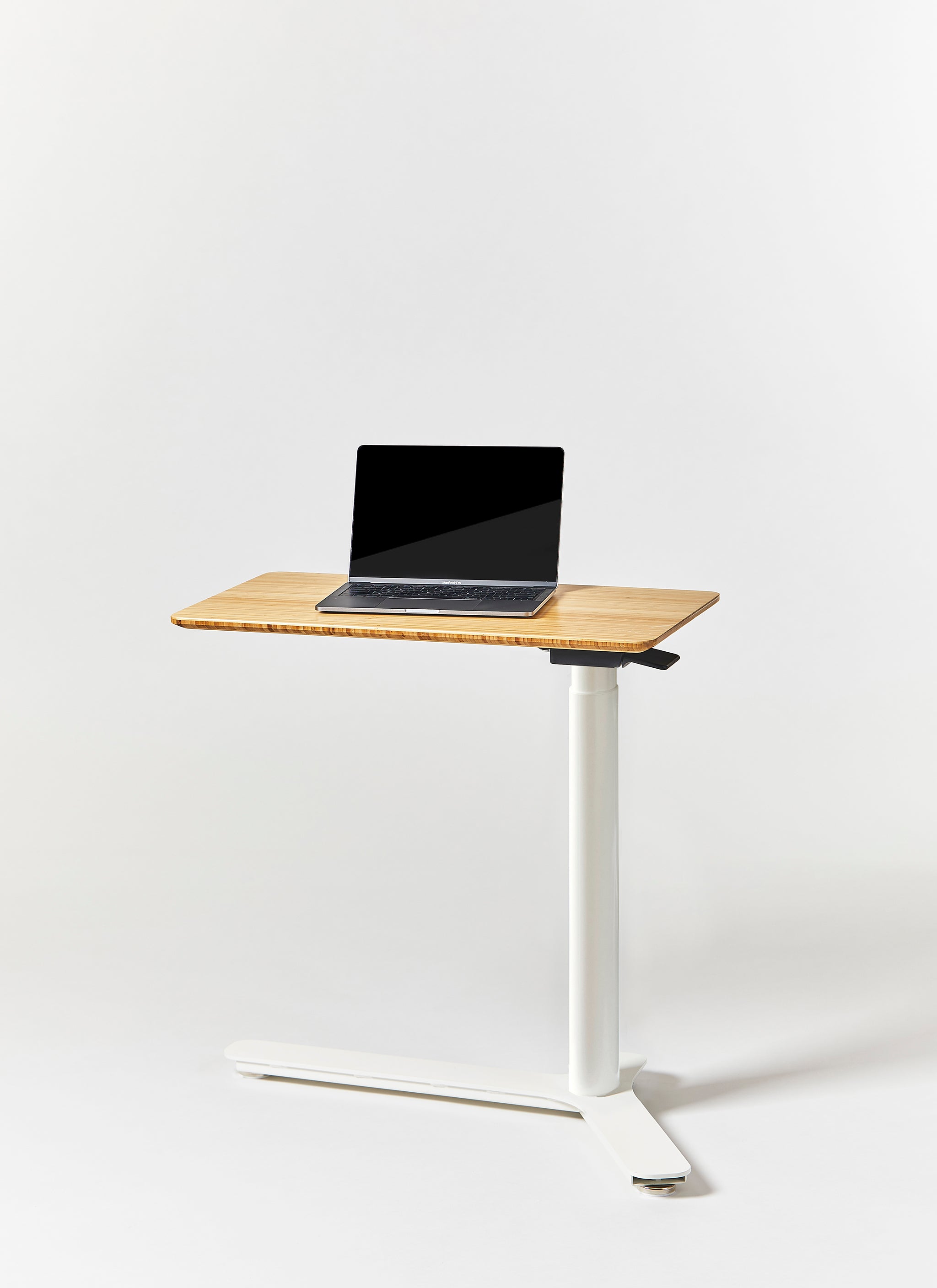 Float Mini height-adjustable desk with natural bamboo top and white base, featuring a laptop for scale.