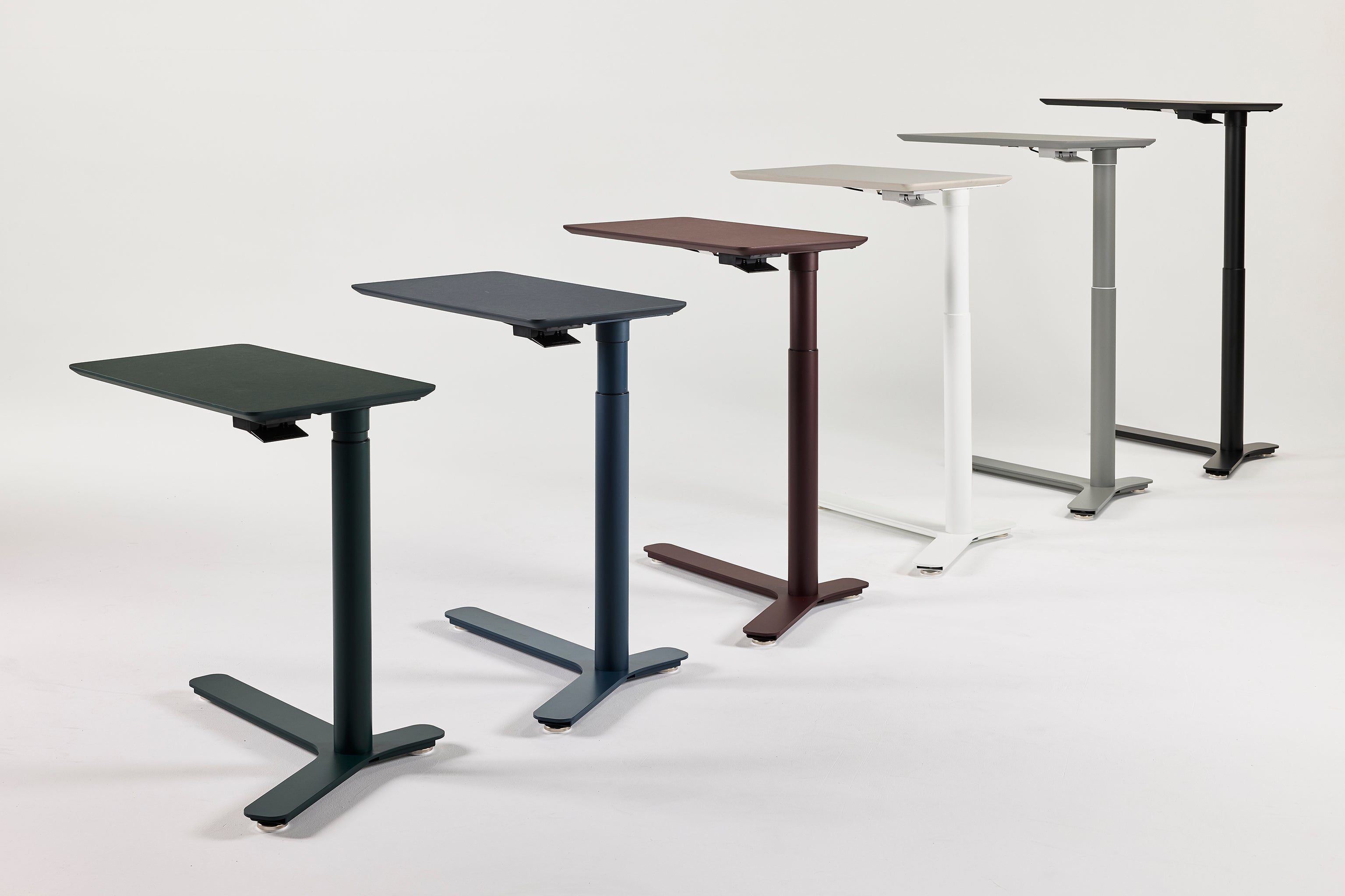 Lineup of Float Mini desks in various colors including green, navy, maroon, white, gray, and black, showcasing compact ergonomic sit-stand solutions.