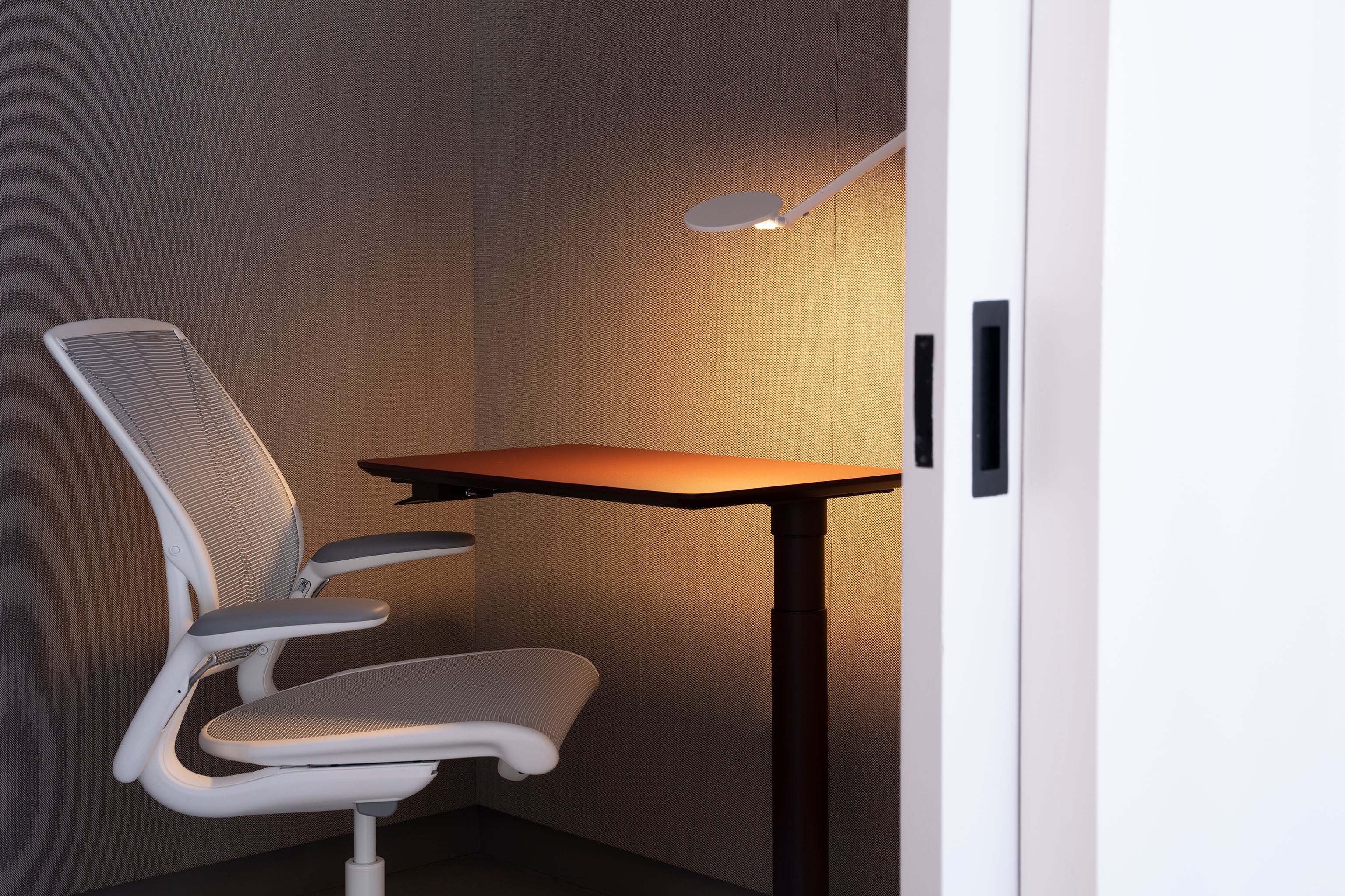Compact Float Mini sit-stand desk paired with a white Liberty task chair in a minimal office nook with accent lighting.
