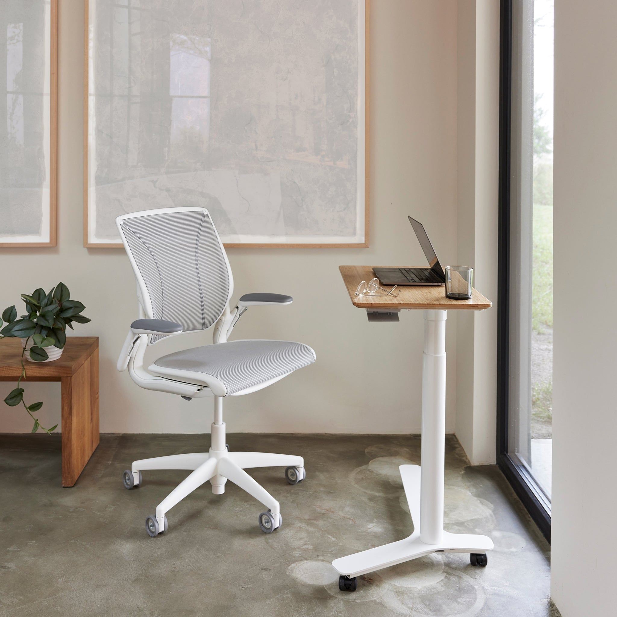 Float Mini sit-stand desk with a white Liberty chair in a serene home office setting, featuring wood accents and natural light.