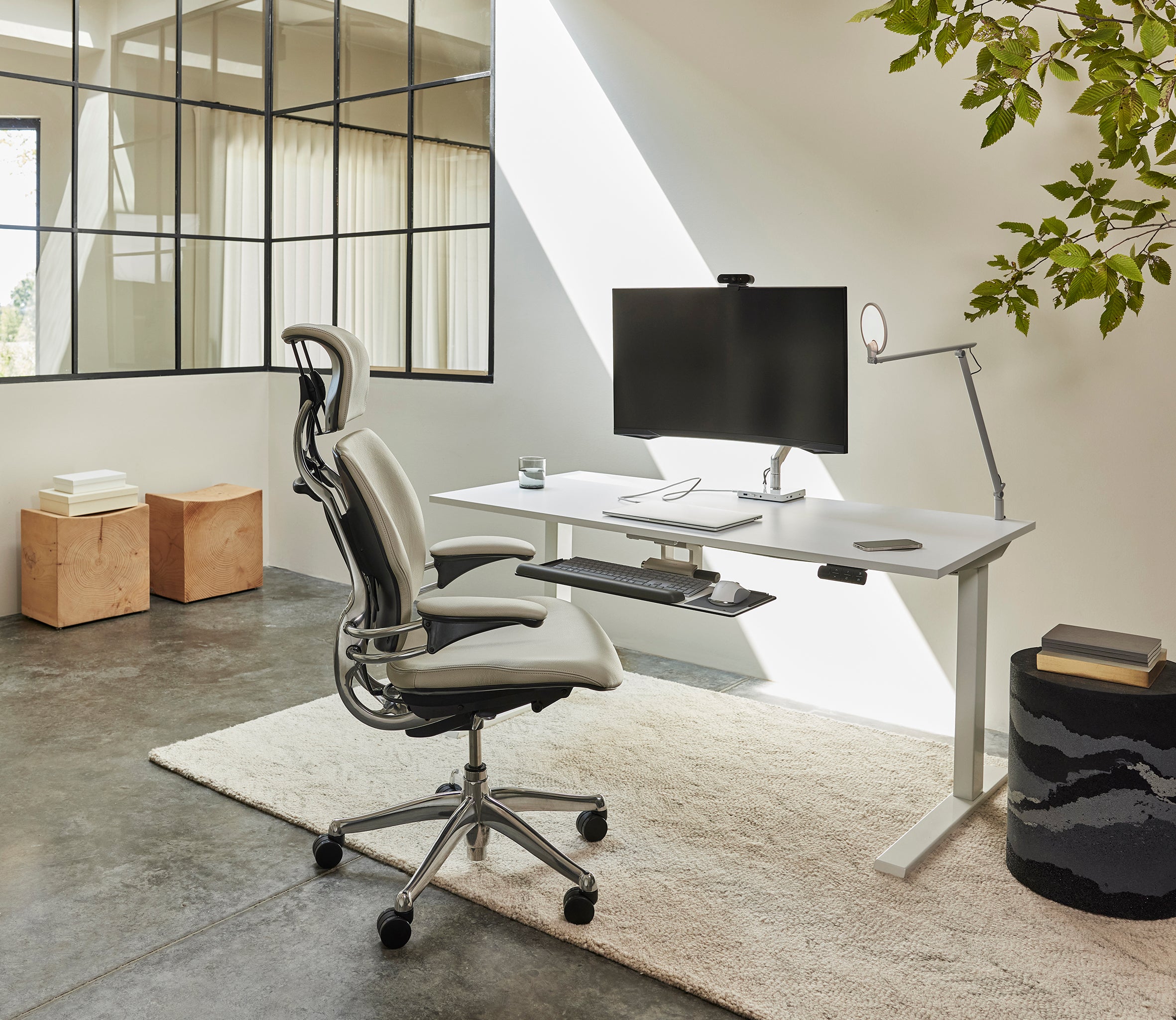 Freedom Headrest ergonomic chair in a minimalist home office setup beside a standing desk and monitor.