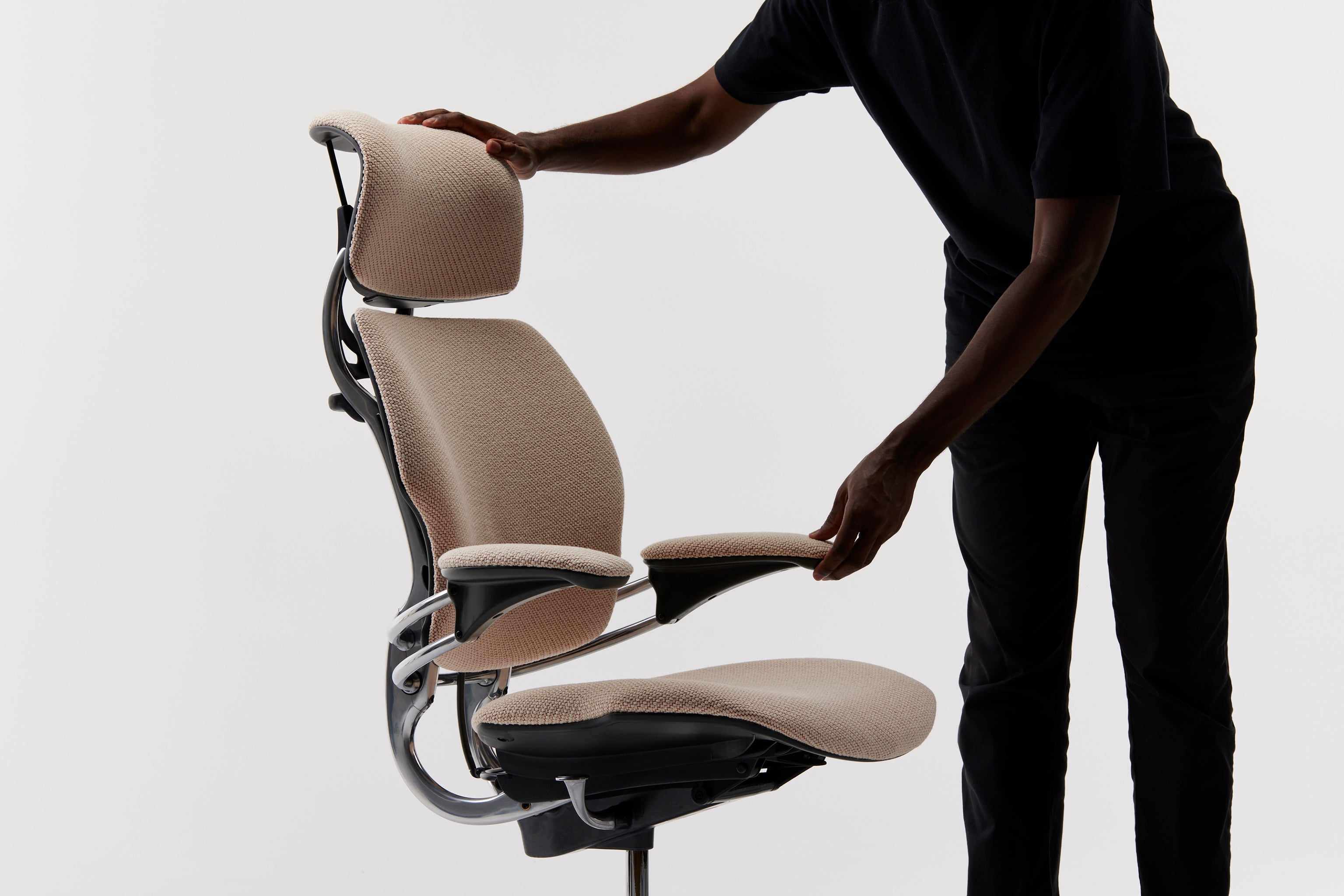 Full side view of Freedom Headrest being adjusted by user, highlighting synchronized armrest and headrest functionality.