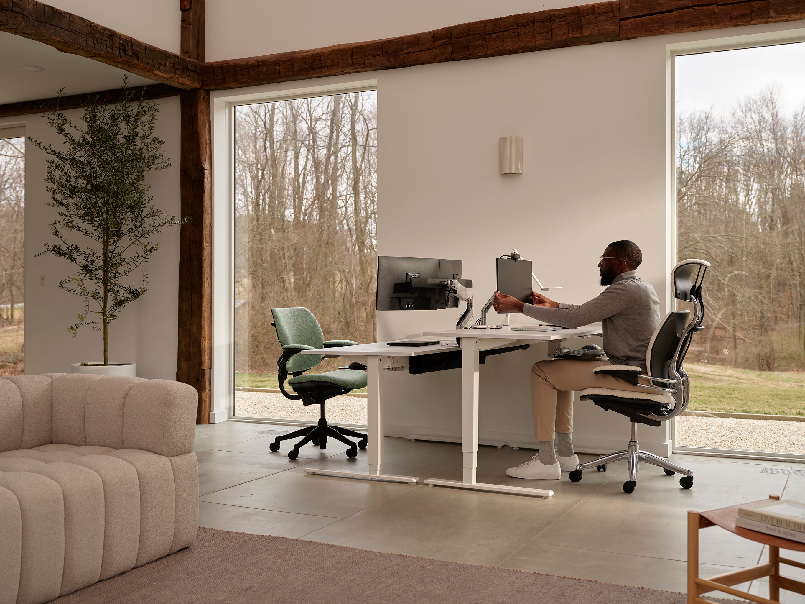 Freedom Task Chair in mint green and Freedom Headrest in black positioned at dual white desks in a modern home office with forest views.