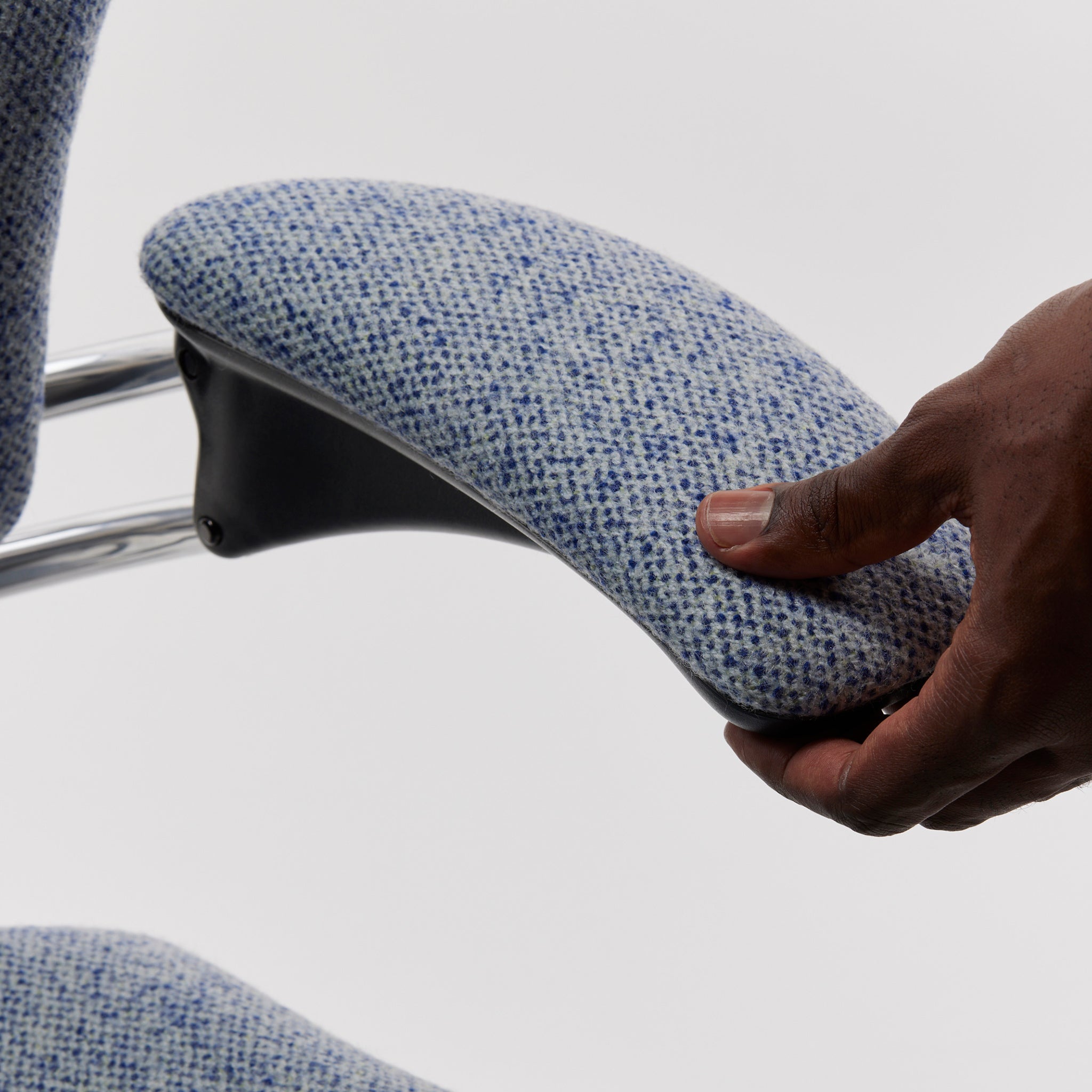 User interacting with the Freedom Task Chair’s padded armrest, emphasizing responsive ergonomic design in blue speckled fabric.