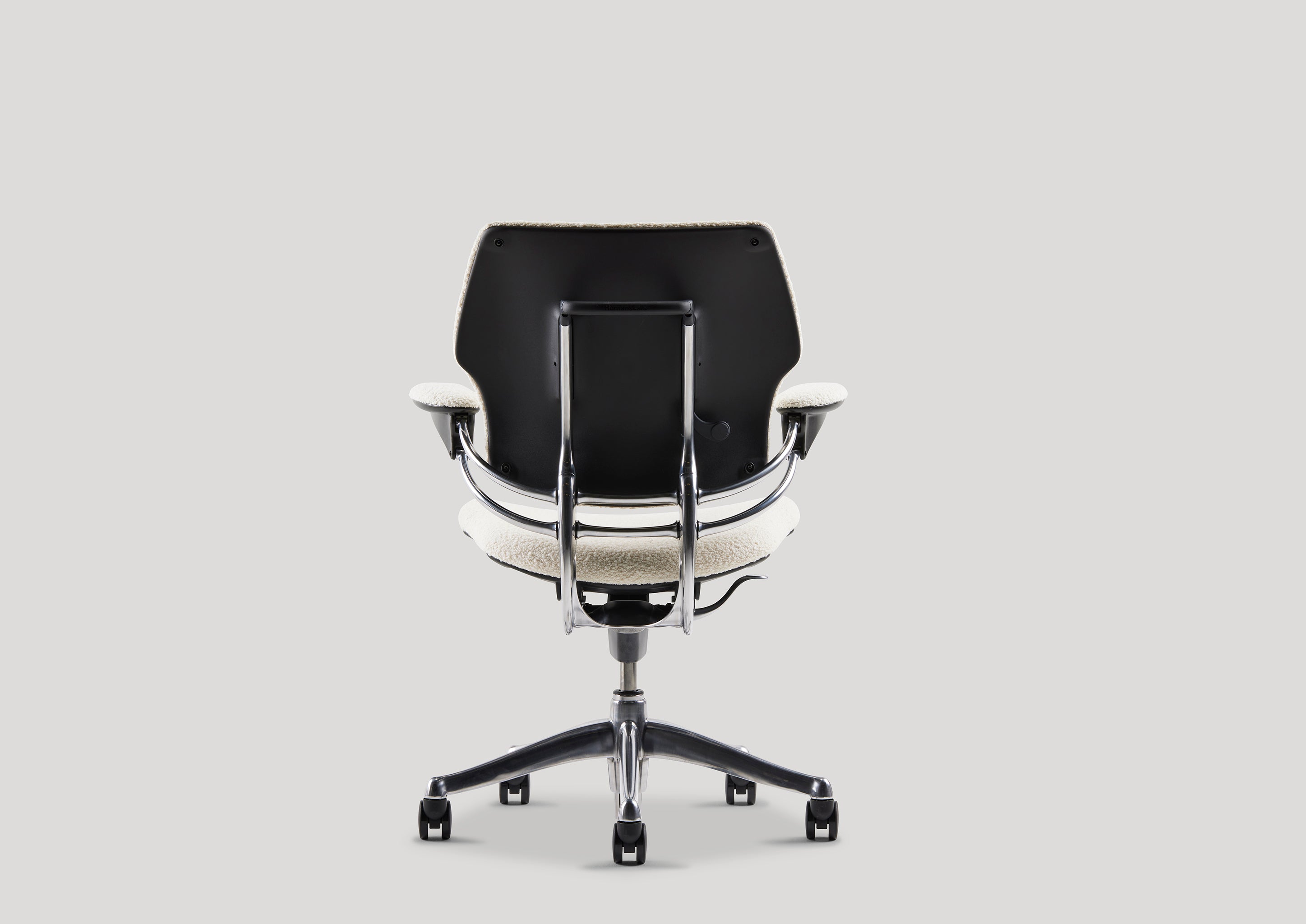 Back view of Freedom Task Chair in white bouclé with black back panel and chrome accents, designed for supportive workspaces.