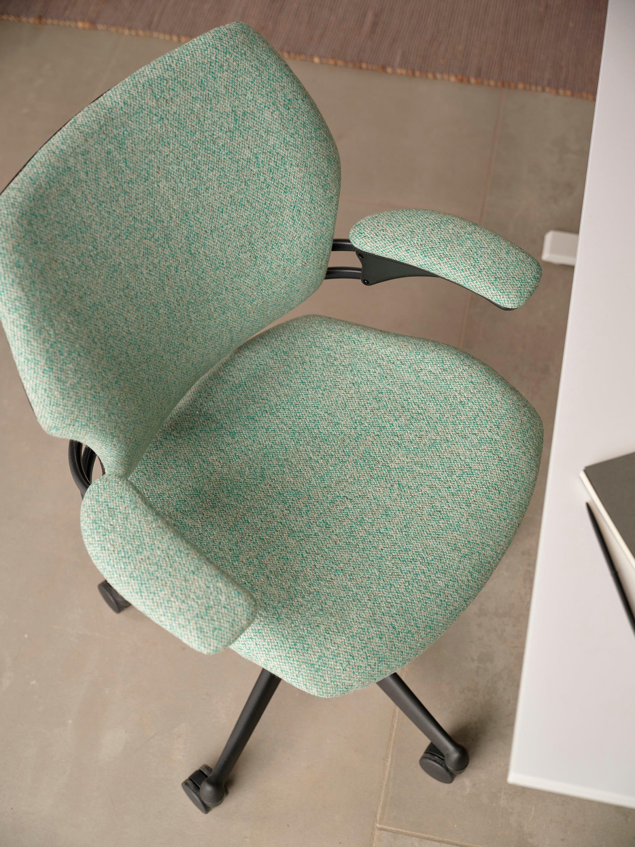 Overhead detail view of Freedom Task Chair in soft green upholstery next to a white desk with neutral-toned flooring.