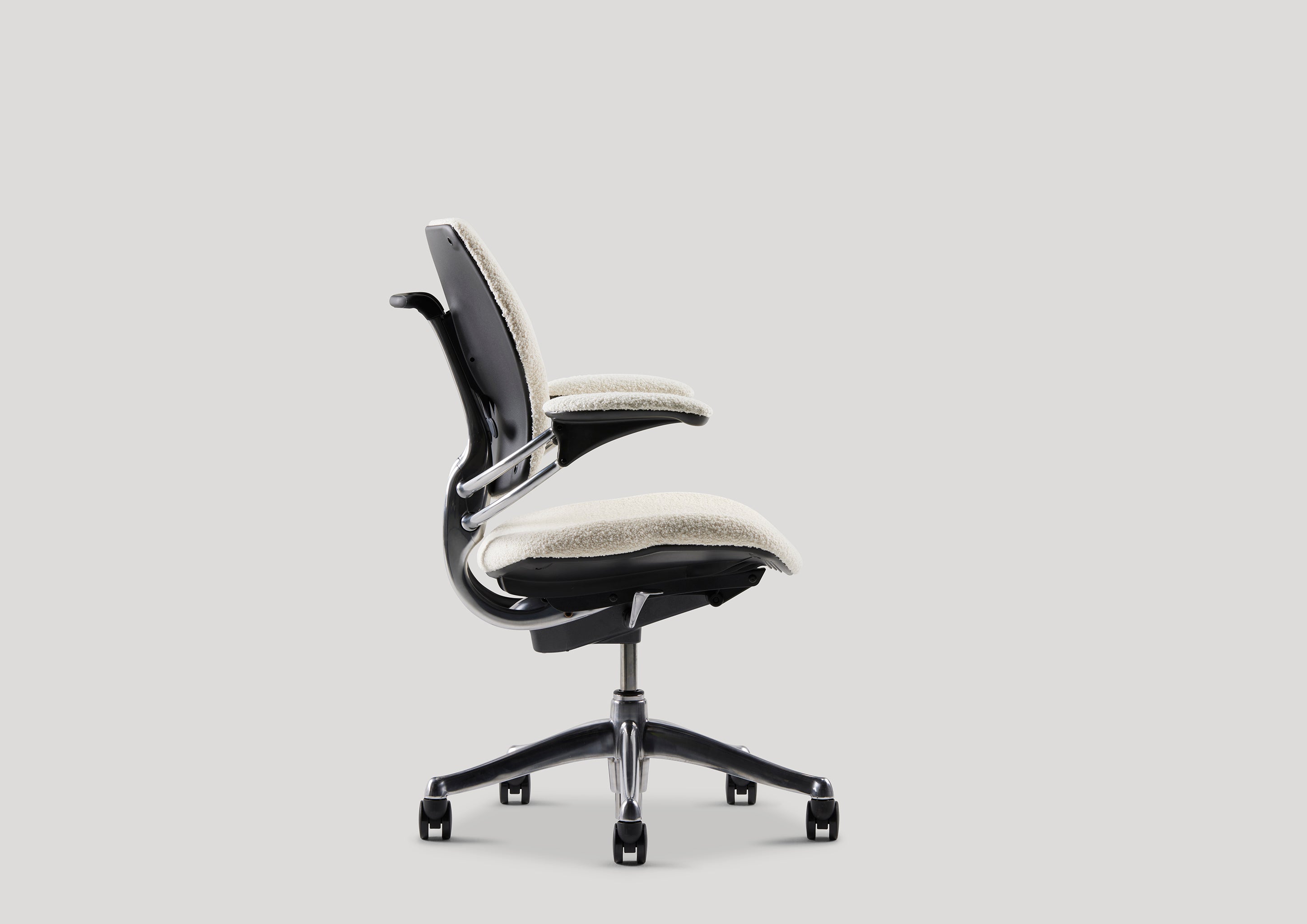 Side profile of Freedom Task Chair in ivory bouclé fabric, highlighting recline range and seat contour over chrome base.