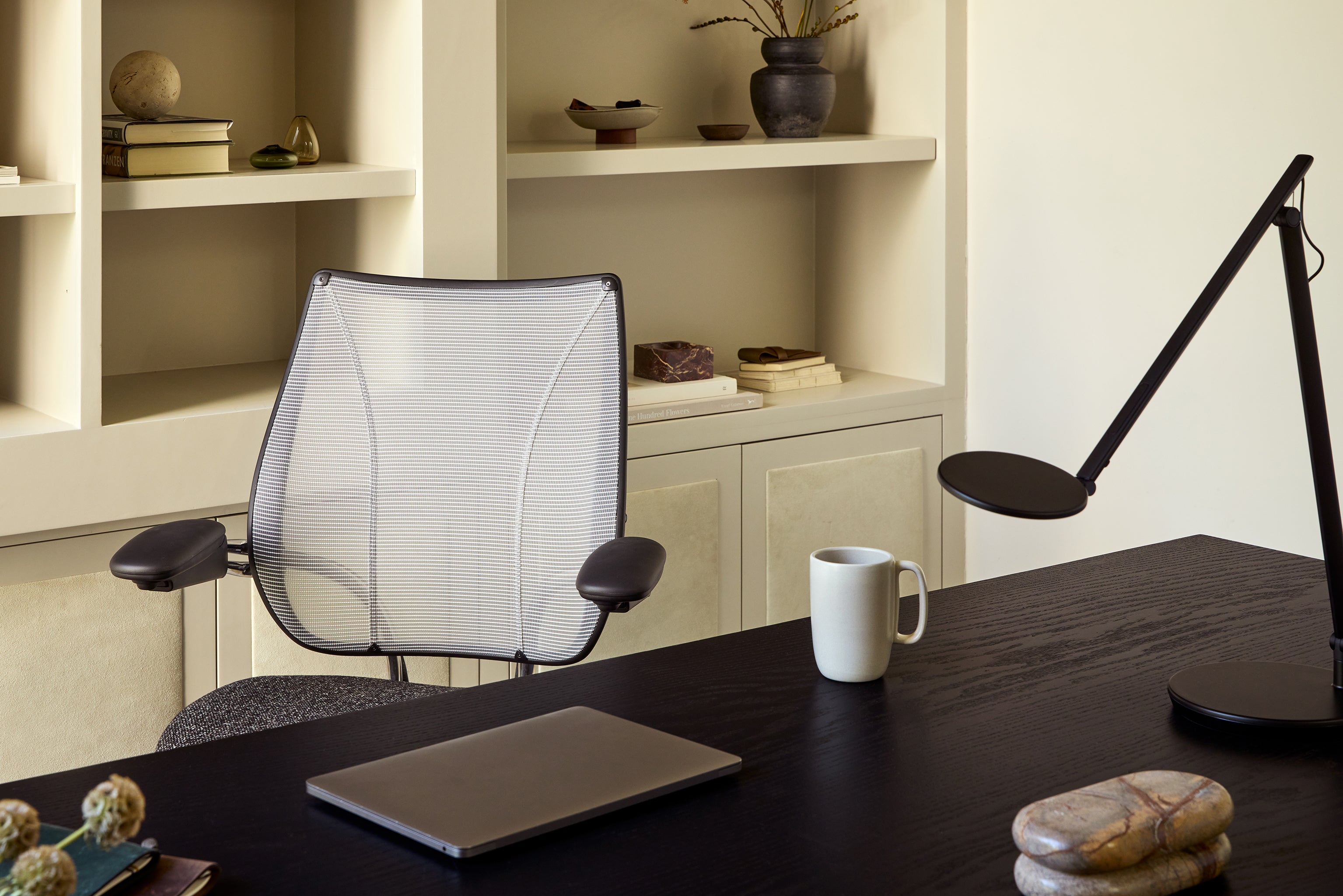Liberty Task Chair with breathable mesh backrest positioned behind a modern black desk in a home office setting.