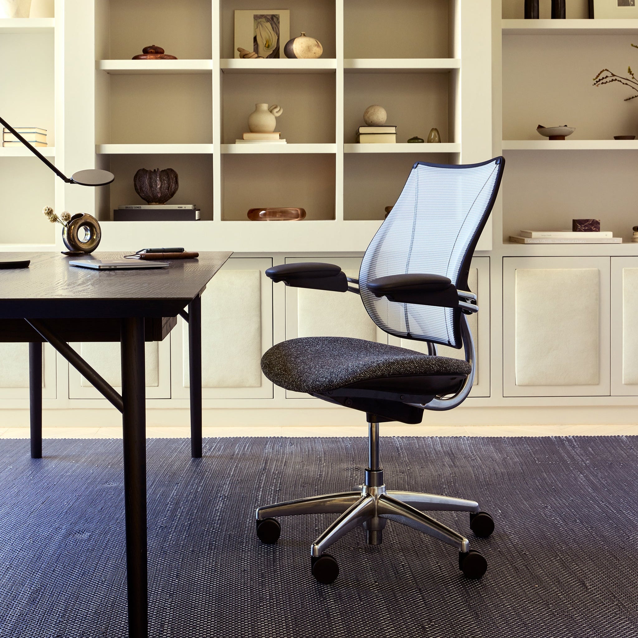 Side profile of the Liberty Task Chair showing its ergonomic mesh back and cushioned seat in a refined home office interior.