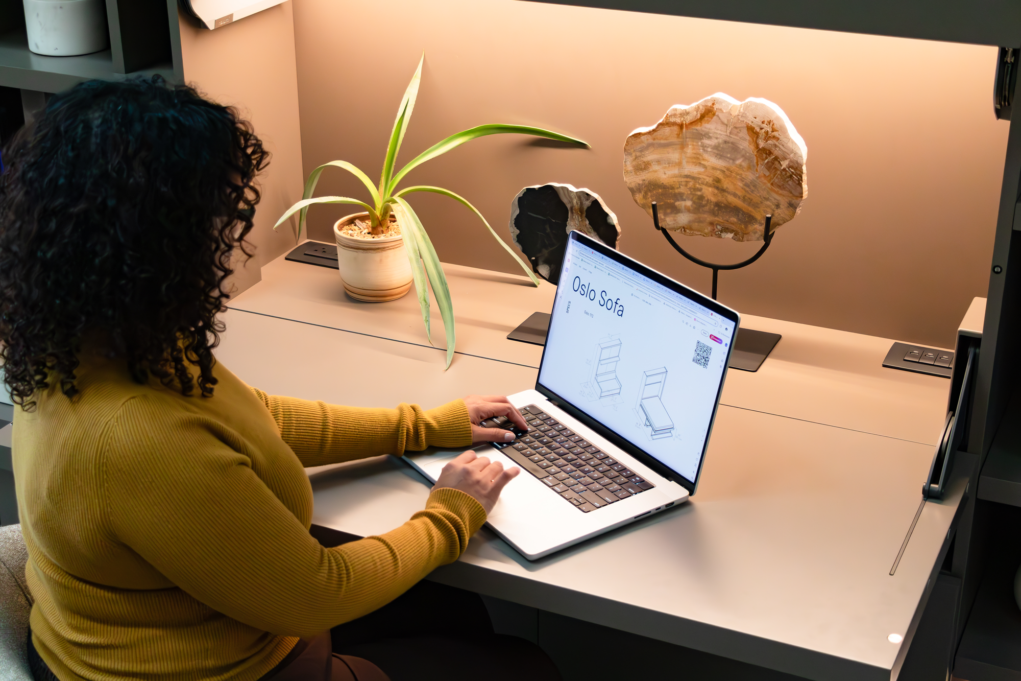Person working at Maxi Desk with laptop and LED shelf lighting at Resource Furniture Los Angeles showroom.