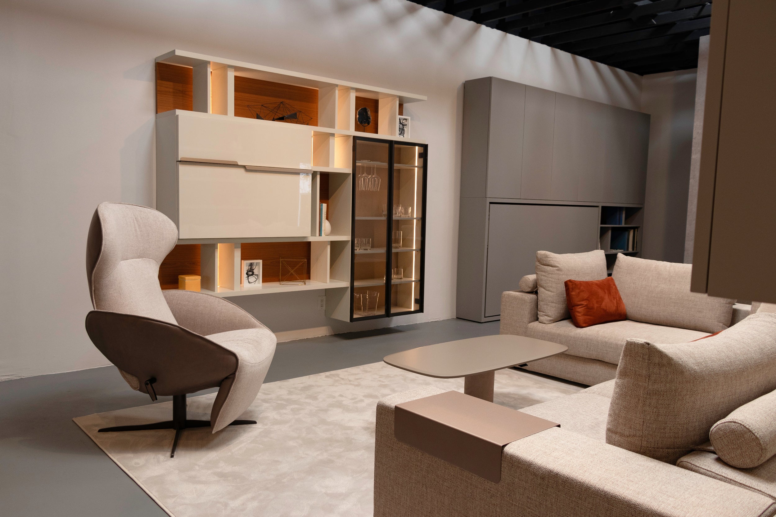 Maxi Bar closed within a custom wall system with open shelving, glass cabinet, and modern lounge seating.