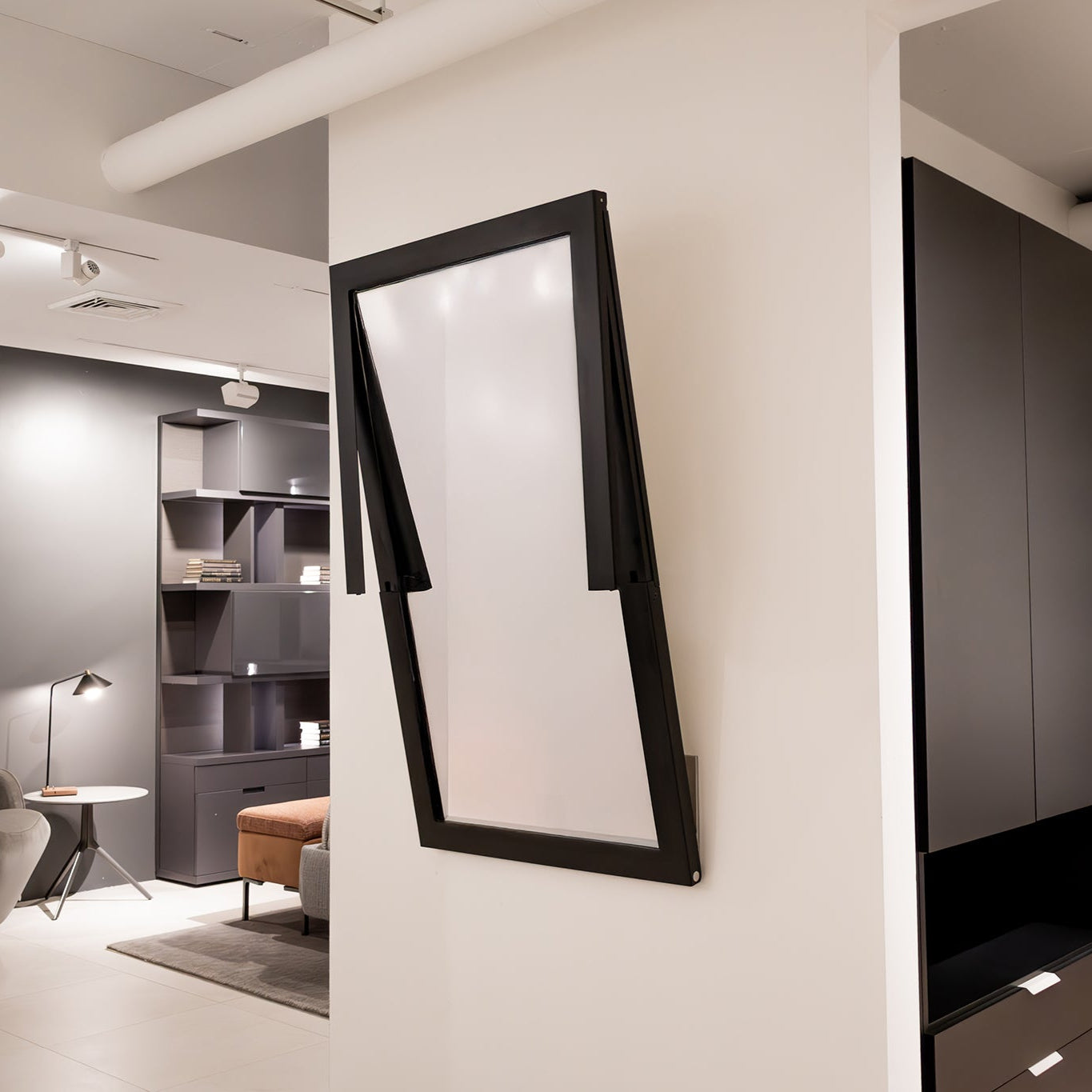 Specchio wall mirror opening into a table, showing space-saving transformation in progress.