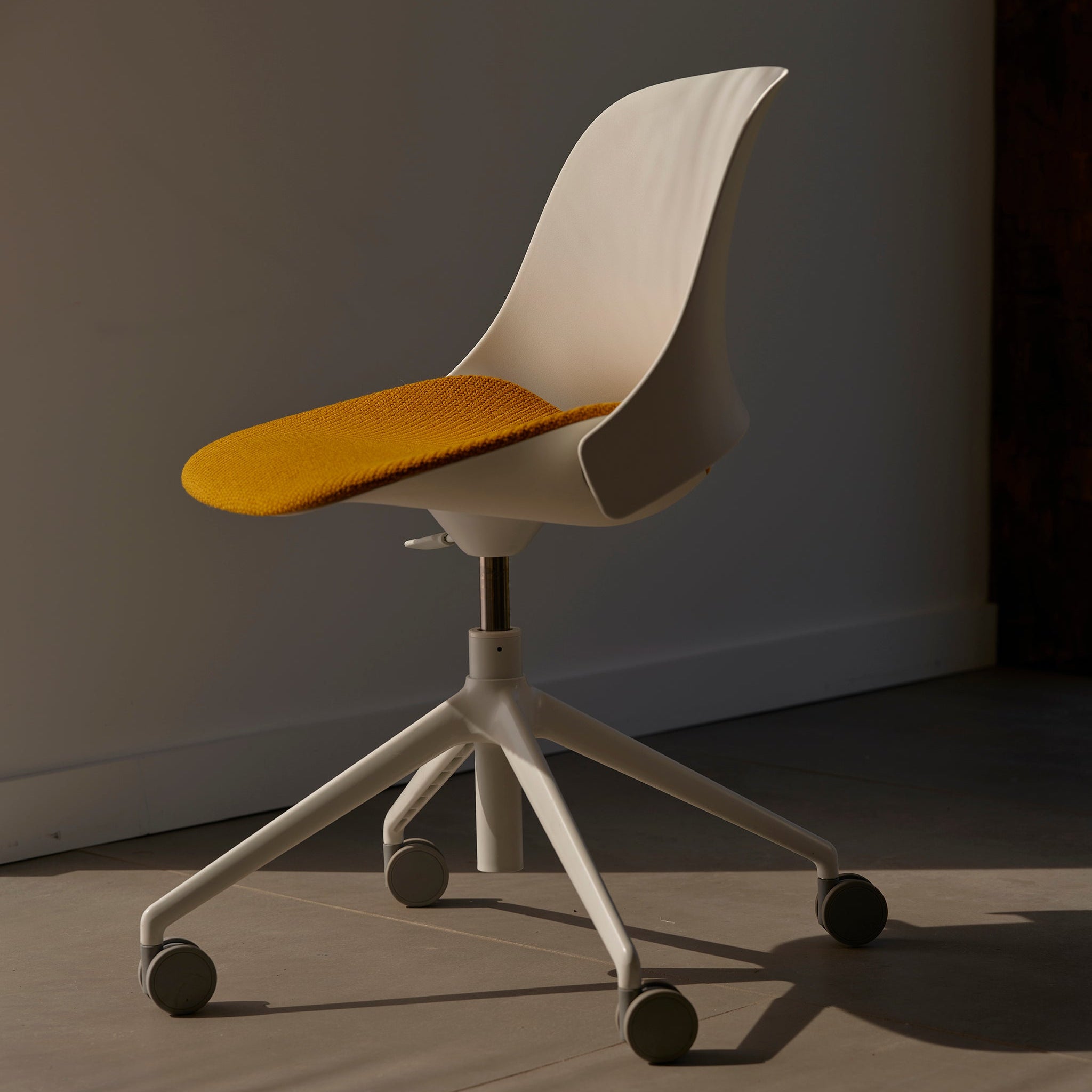Close-up of the Trea Chair’s sculpted white base and polished aluminum frame, highlighting its modern ergonomic design.
