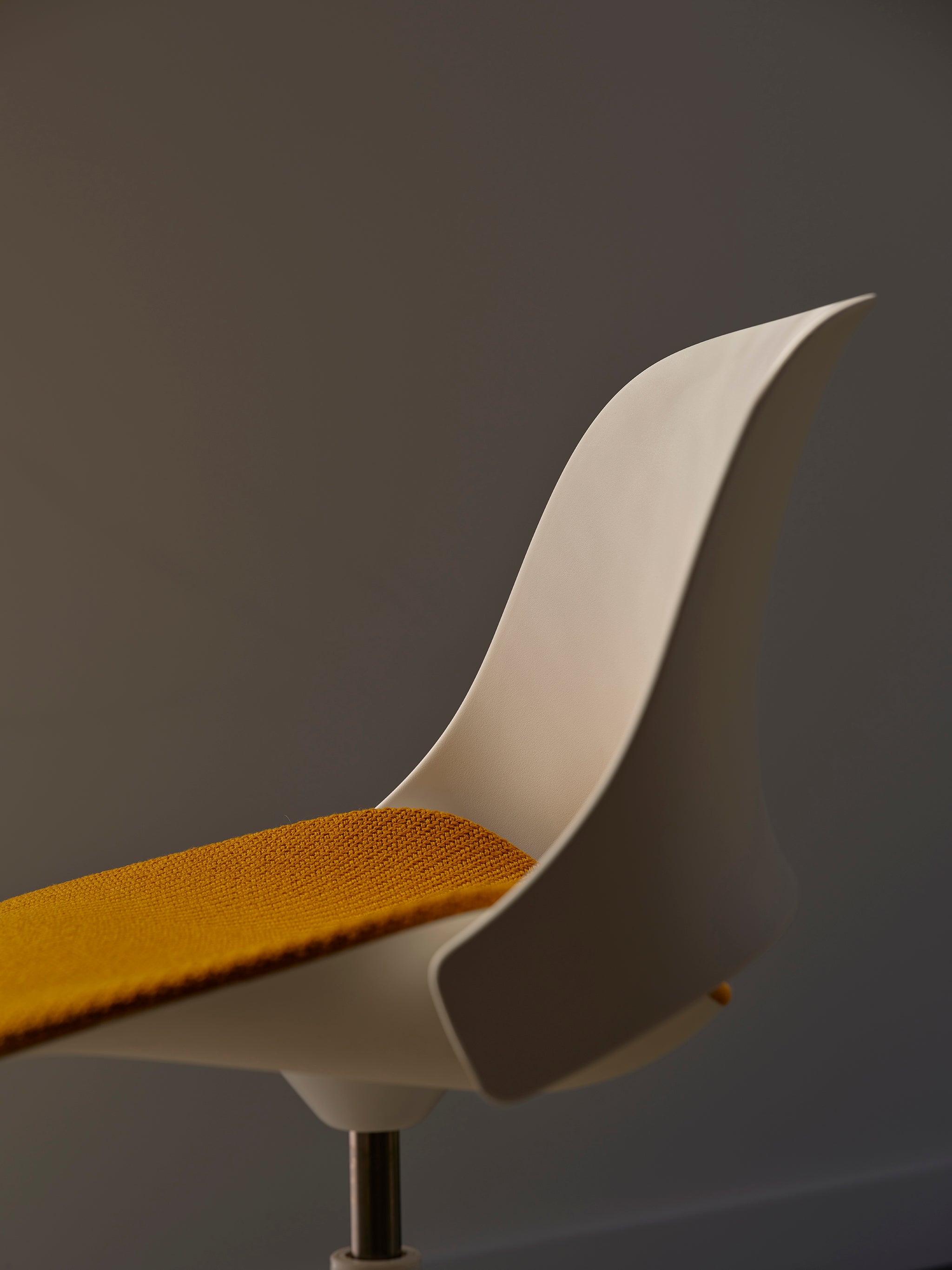 Side view of the Trea Chair in white with a yellow seat, emphasizing its clean profile and contemporary silhouette.