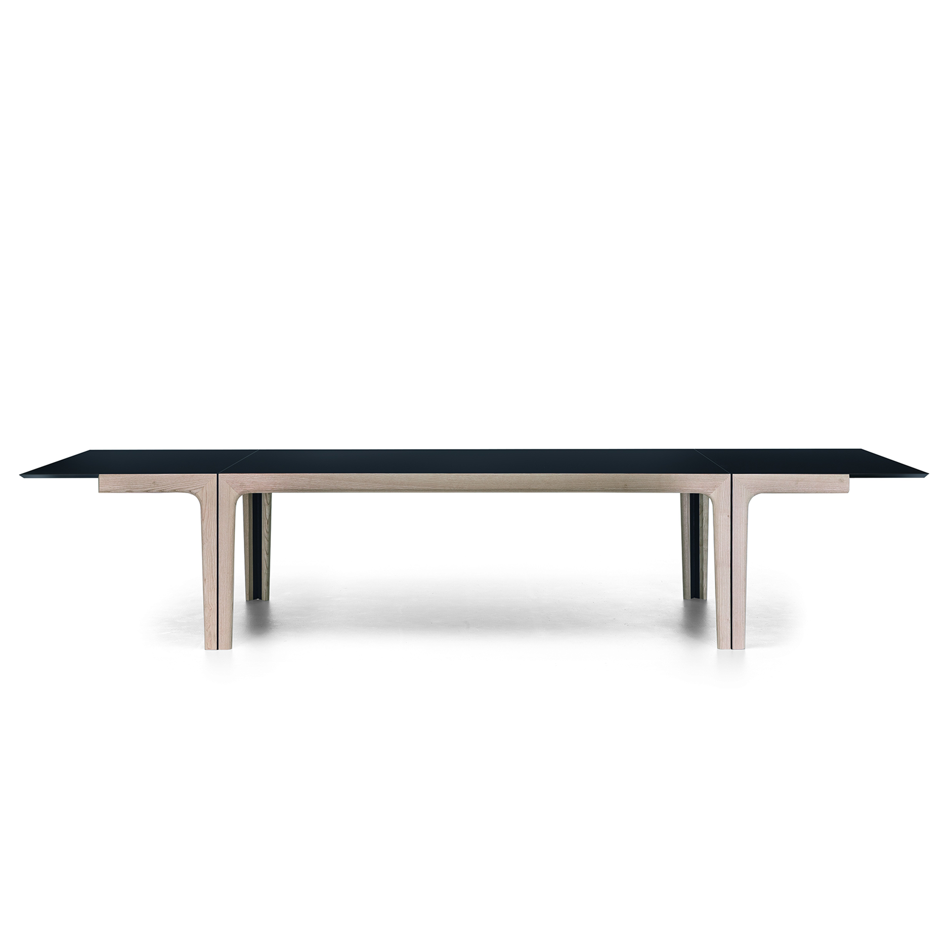 Amalong dining table fully extended with black tabletop and light ash wood base, featuring hidden extension leaves.