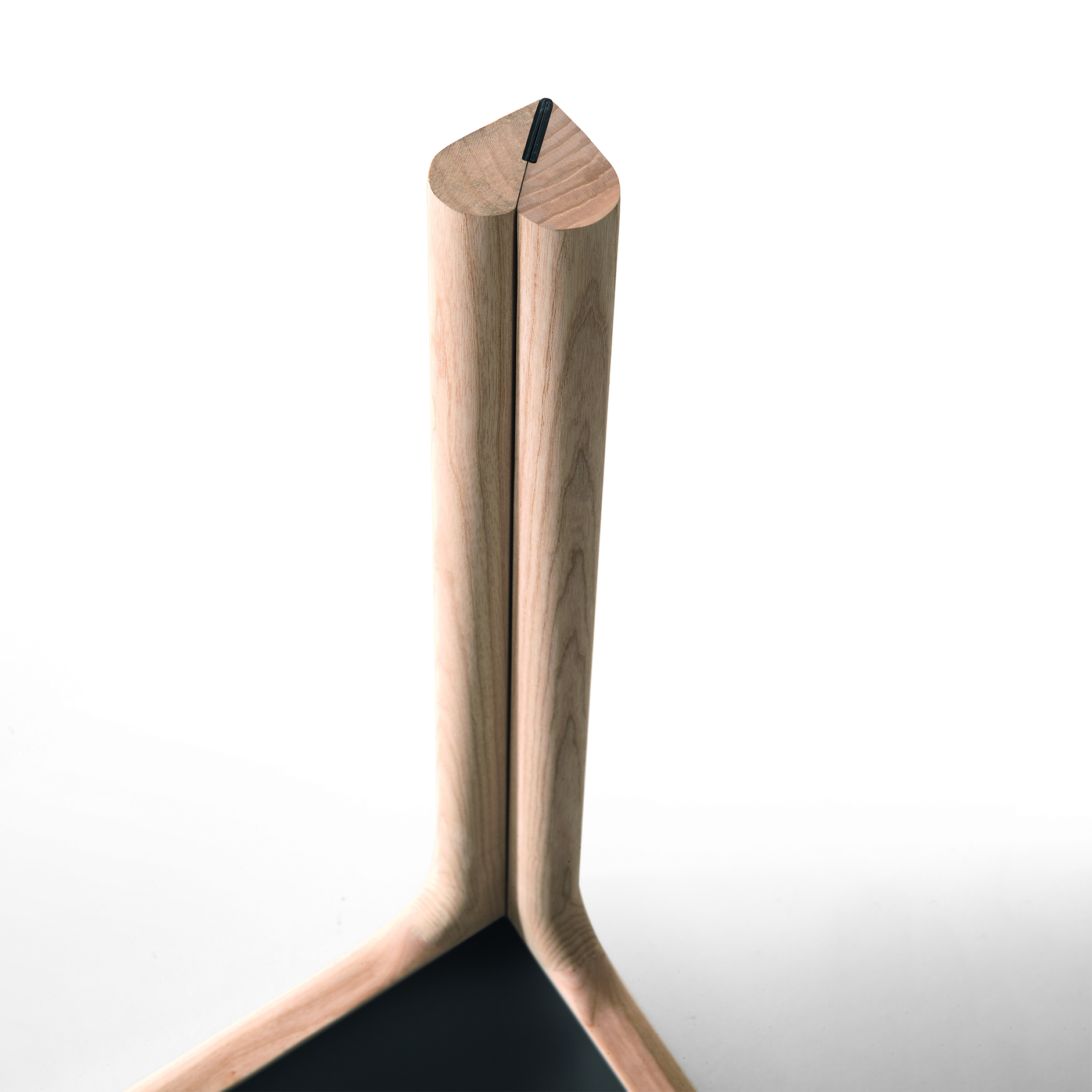 Detail view of Amalong table leg showing signature heart-shaped joinery in ash wood beneath the tabletop.