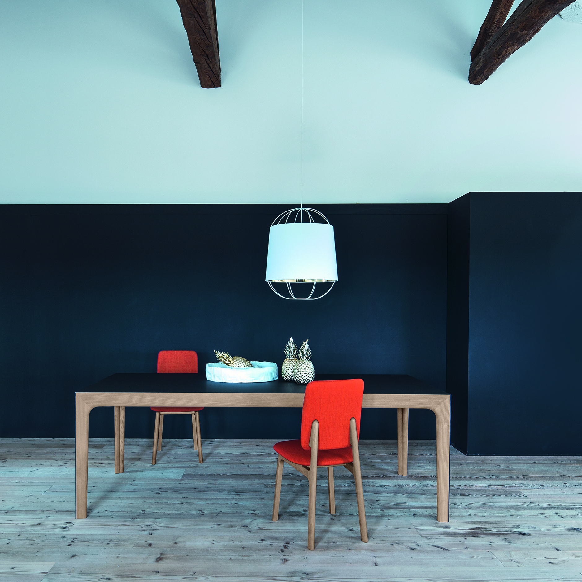 Amalong Extension Table in walnut finish with black top, styled with red dining chairs and modern pendant light in a contemporary space.