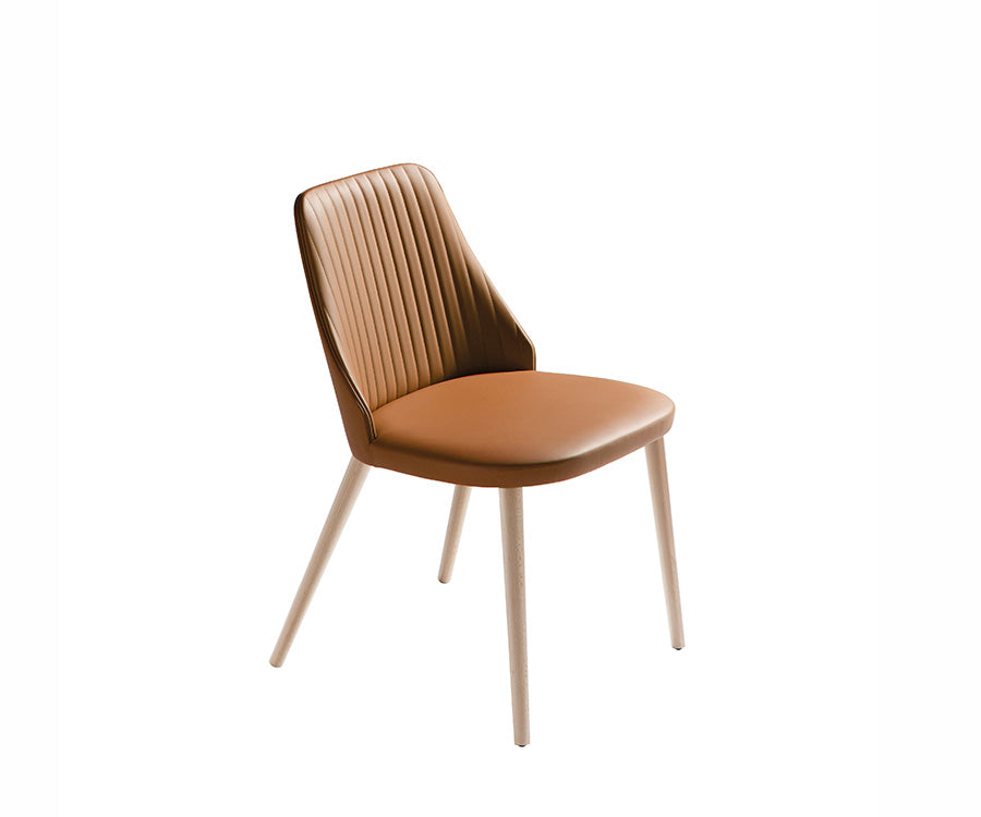 Side view of Break Dining Chair in tan leather with vertical quilting and natural beechwood legs, shown on white background.
