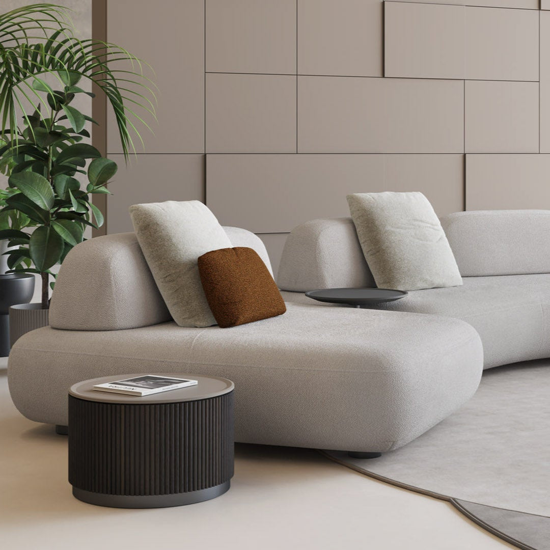A modern living room with the Art Nova Curve sectional sofa in soft neutral upholstery, styled with sculptural cushions and low-profile tables.