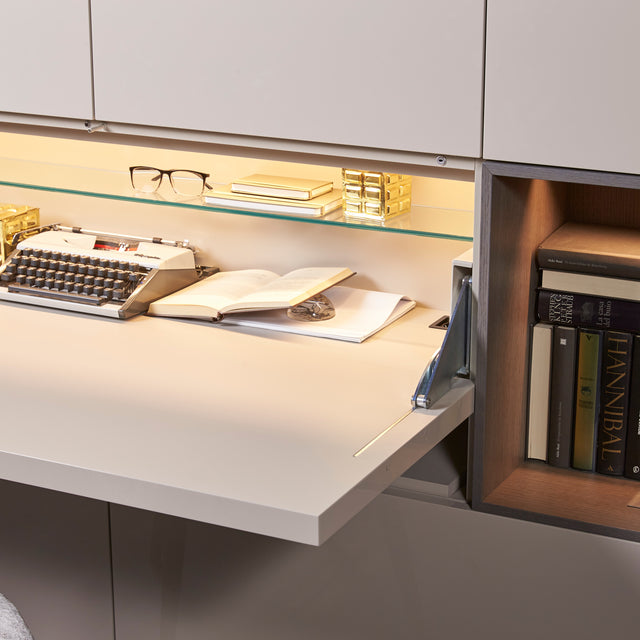 Custom cabinetry units with wall-mounted desk detail showing books, lighting, and workspace accessories — modern space-saving furniture by Resource Furniture.