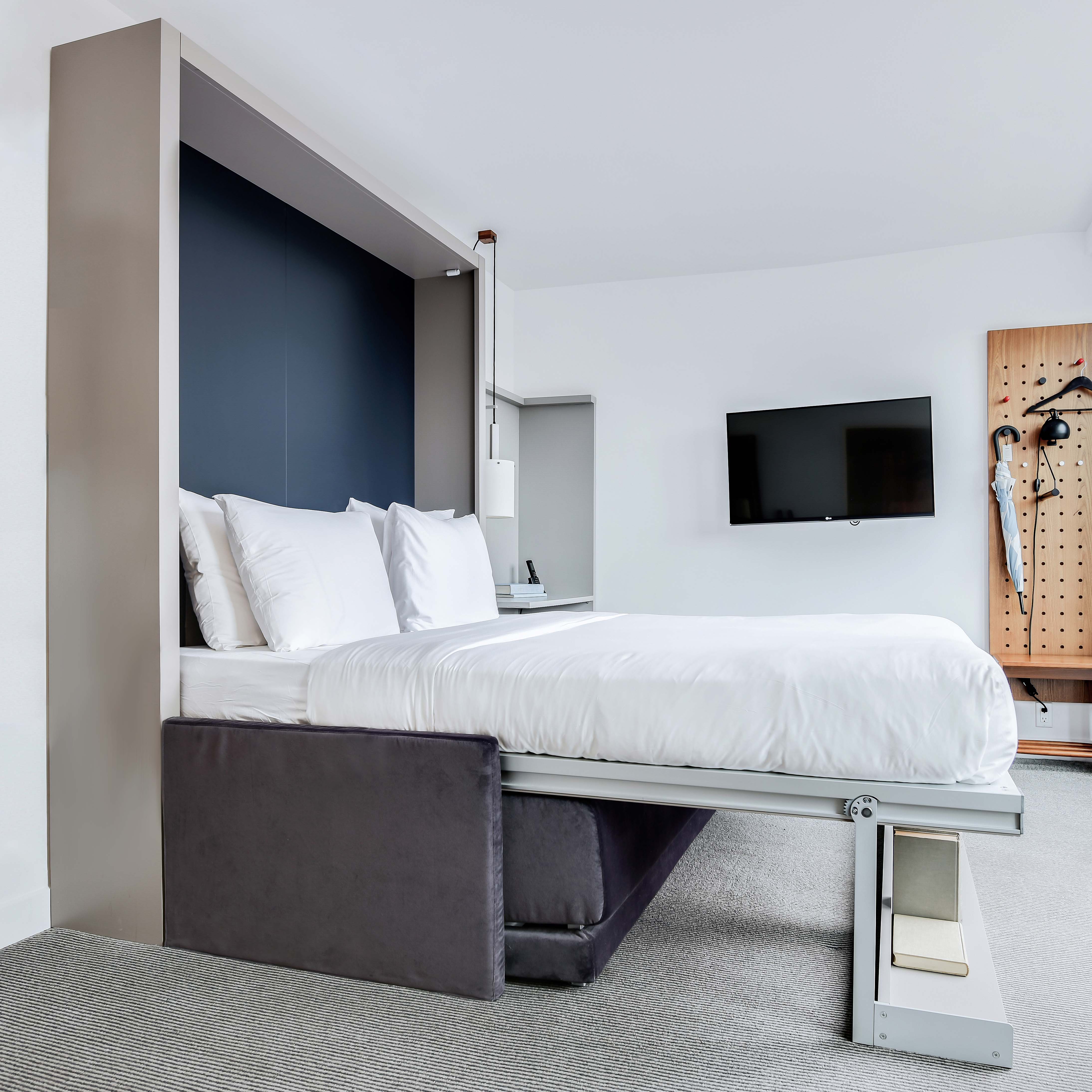 Oslo Sofa Queen Murphy Bed with Hidden Storage shown open in a sleek hotel-style bedroom with minimalist design