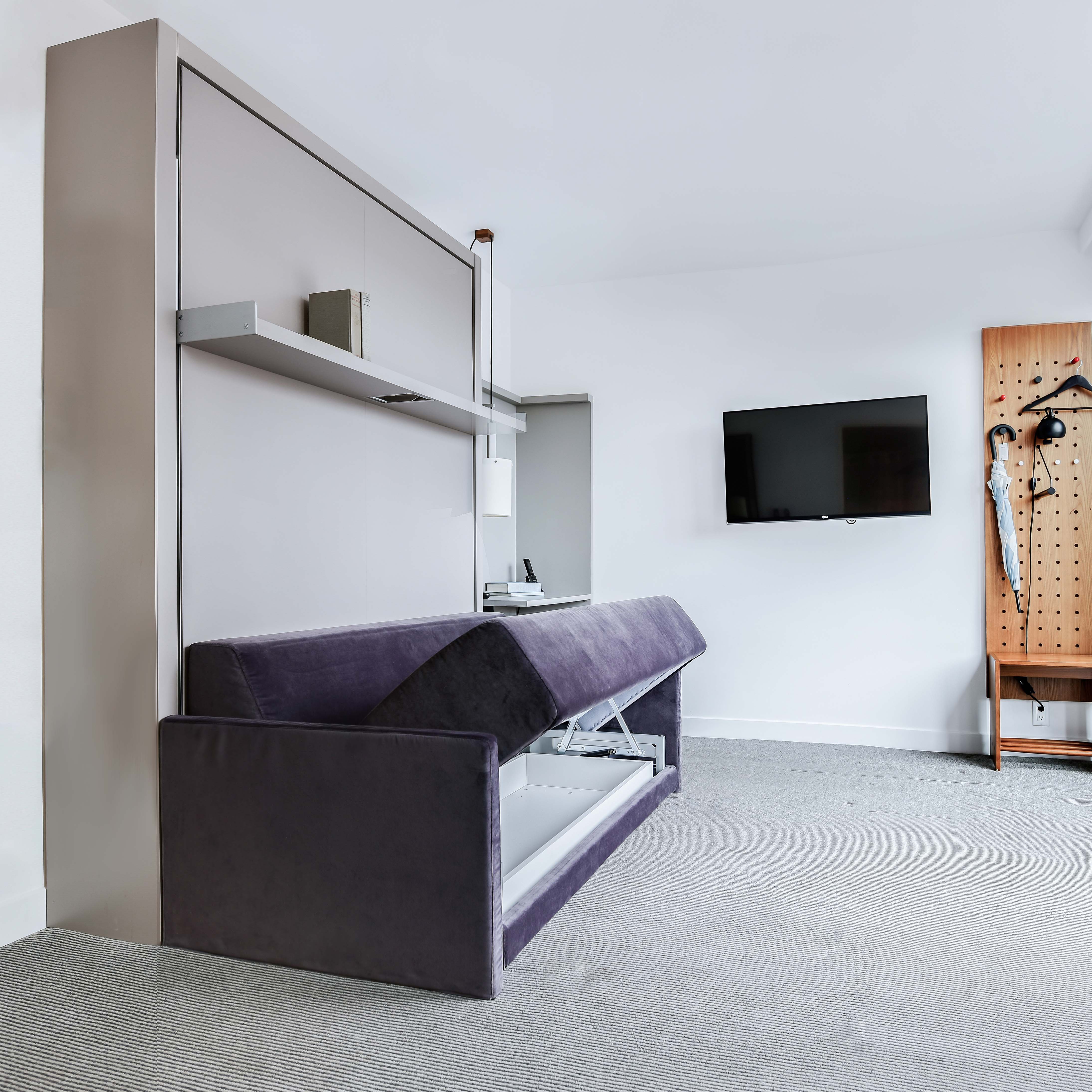 Oslo Sofa Murphy Bed with storage compartment open, revealing hidden space-saving furniture functionality in a modern hotel room