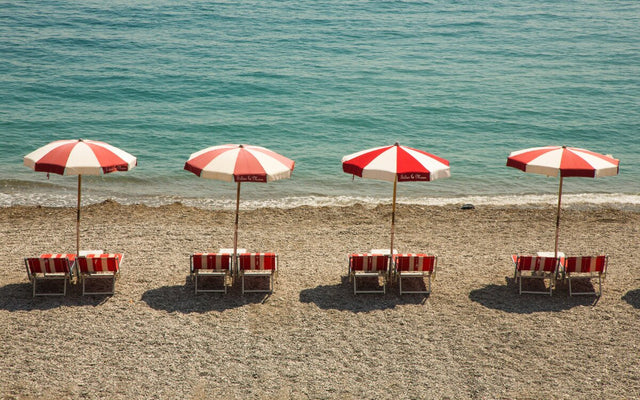 Beach umbrellas on an Italian coastline representing summer lead times for Italian furniture.