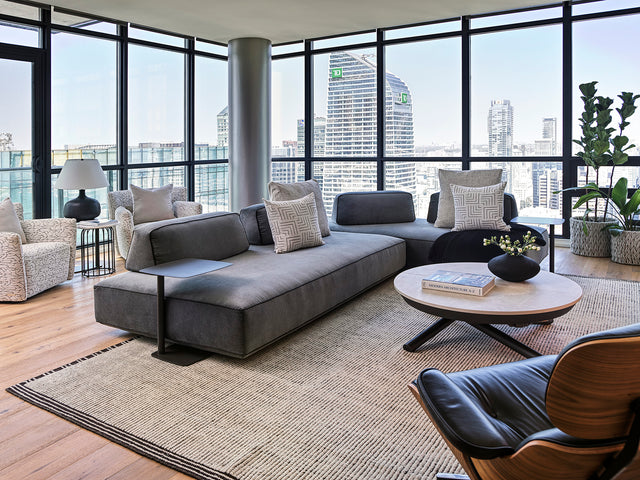 A contemporary living room featuring the Flex Sectional, Flex Side Tables, and Soleil coffee table, with floor-to-ceiling windows showcasing panoramic views of Toronto’s skyline.