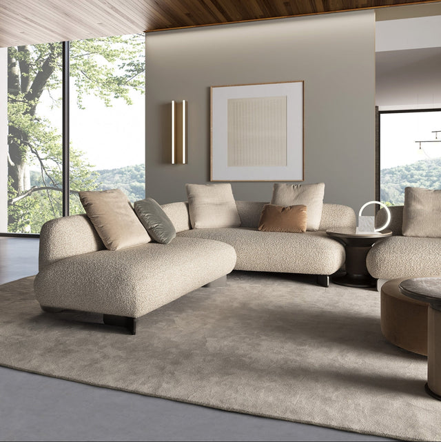 Modern living room featuring beige modular sofas, Bobbin side tables, and a neutral palette, with natural light streaming through large windows.