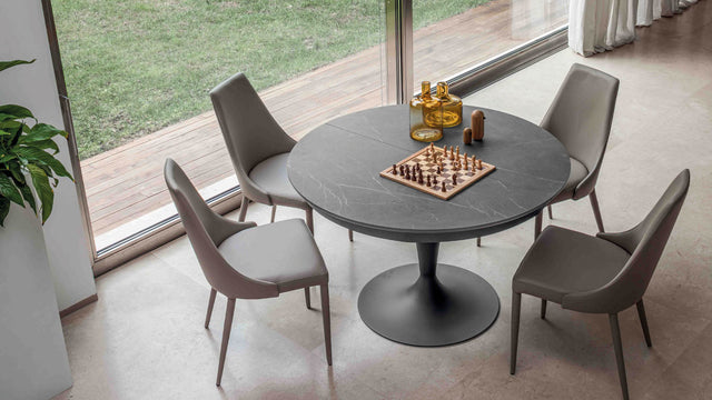 Luna Maxi table in a modern dining space, set as a round table with elegant chairs and minimalist decor, featuring a chessboard centerpiece.