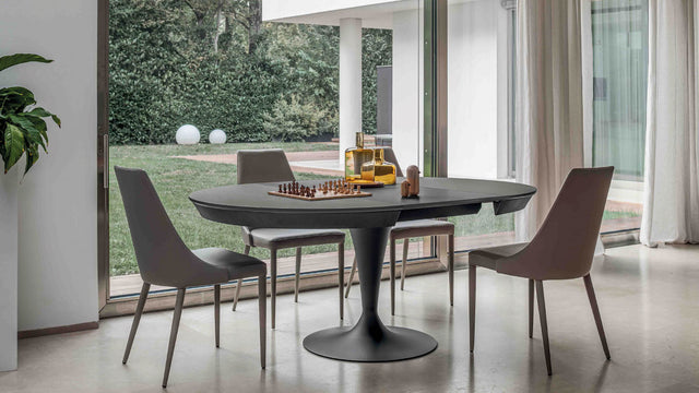 Luna Maxi table fully extended into an oval shape, comfortably seating four in a contemporary dining room with floor-to-ceiling windows.