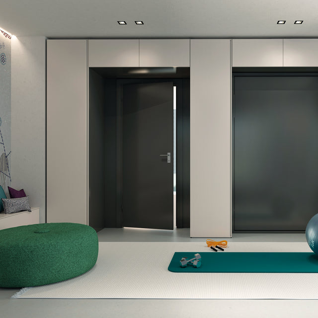 Integrated wardrobe system with sleek white cabinetry and a hidden wall bed in a green finish, featuring an open multipurpose space.