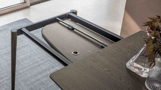 Underside view of the Surf table in wood veneer finish, featuring its sturdy frame and functional extension hardware.