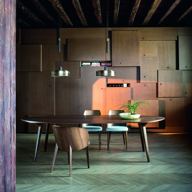 Ademar round wood dining table in a modern dining room with upholstered chairs