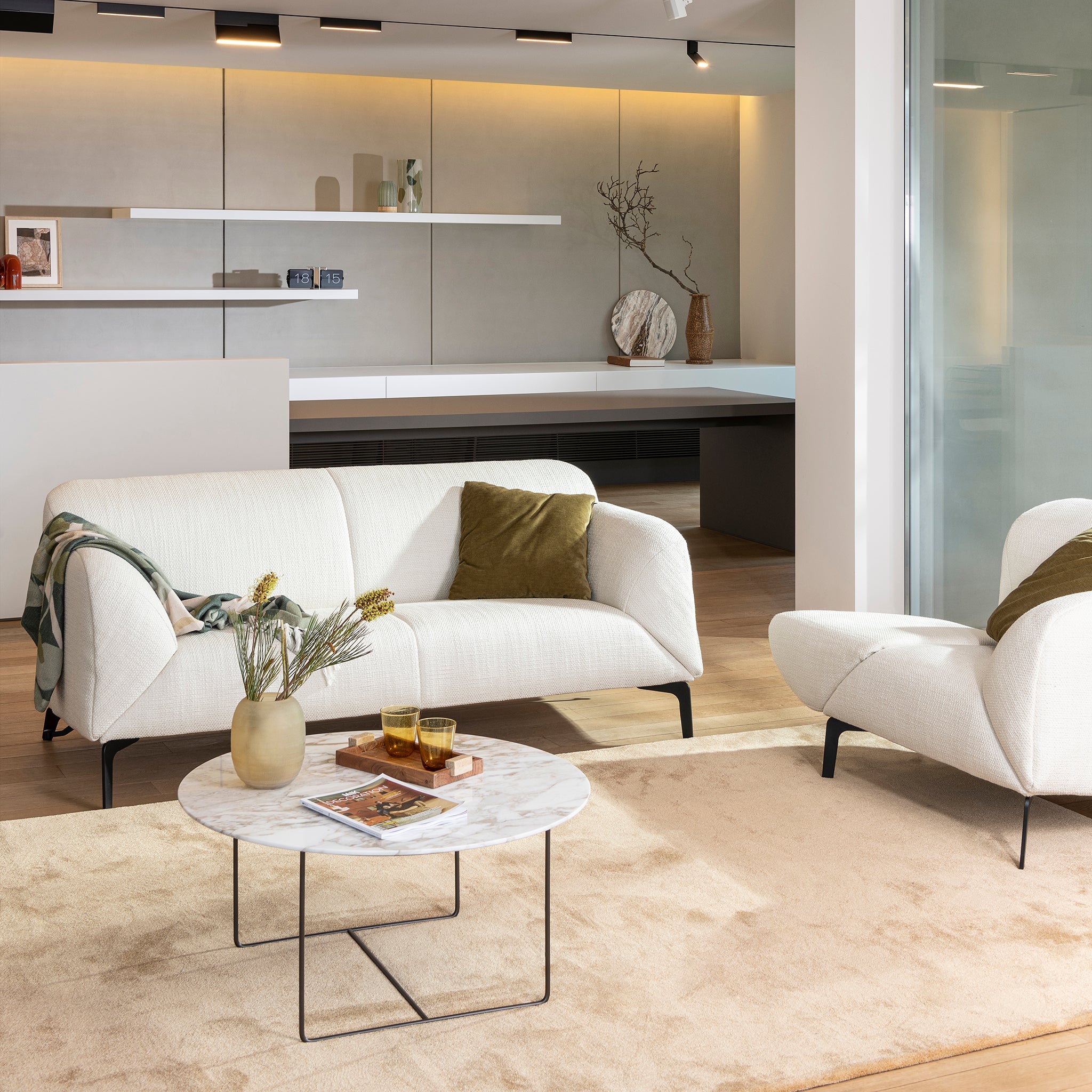 Como Sofa in ivory fabric with green accent pillow and marble coffee table in open-plan interior