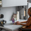 Woman working on a laptop at a flip-down desk system, designed for compact home office use.