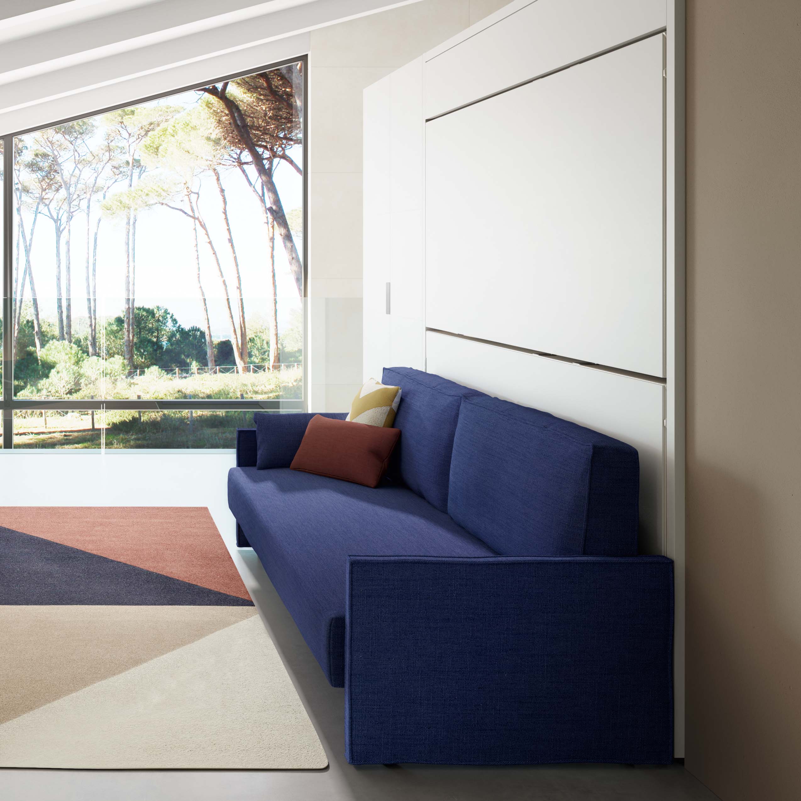 Kali Duo Murphy bunk beds with sofa in a modern room, closed wall bed configuration with blue upholstered couch and sleek white cabinetry – space saving furniture solution.