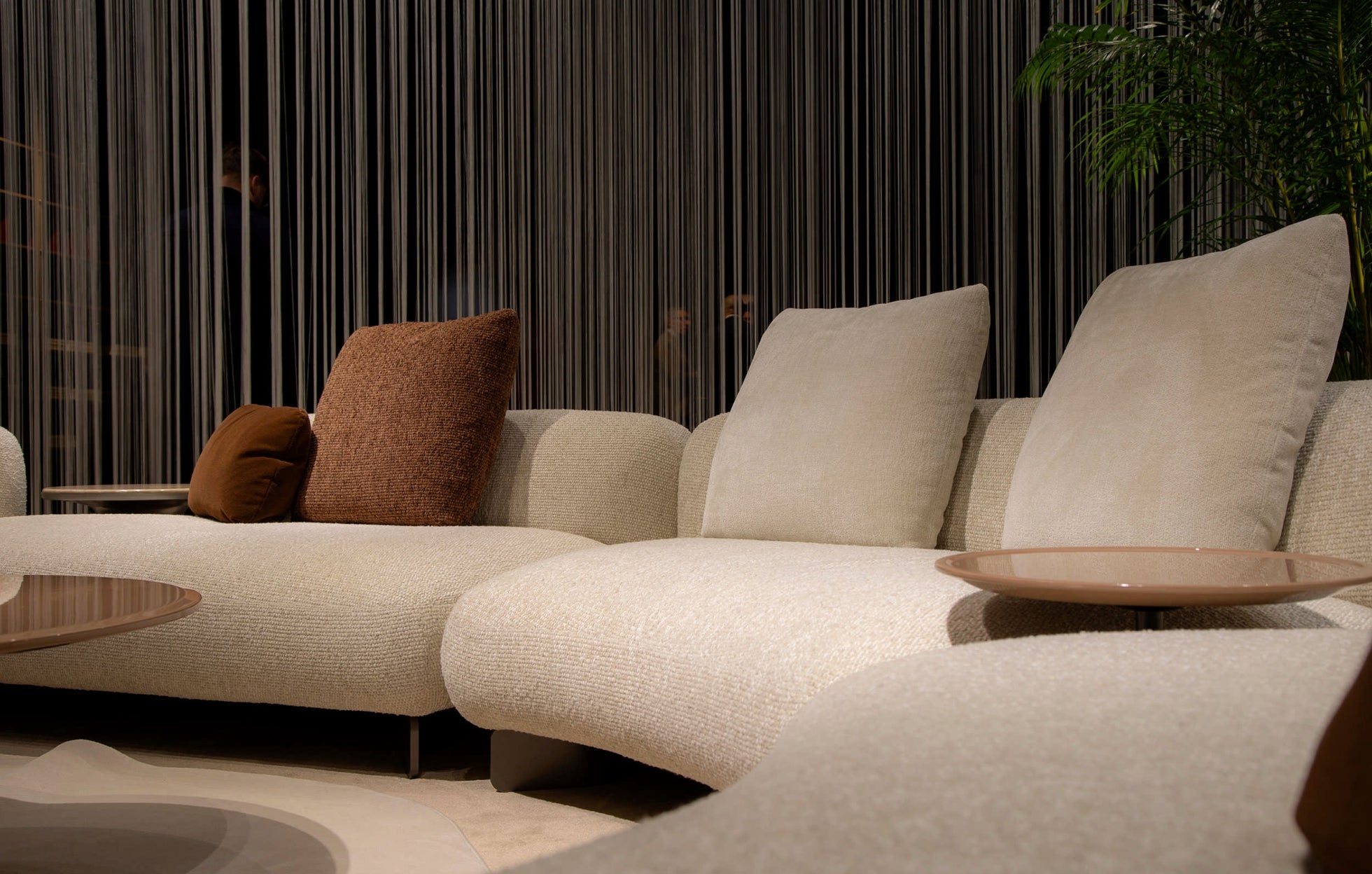 Close-up of Kintai modular sofa’s Italian design with textured upholstery, taupe and brown cushions, and curved sectional profile.