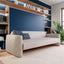 Resource Furniture Minerva horizontal Murphy bed with integrated sofa and walnut shelving — beige upholstered sofa in front of closed navy wall bed; multifunctional, space-saving furniture for small spaces.