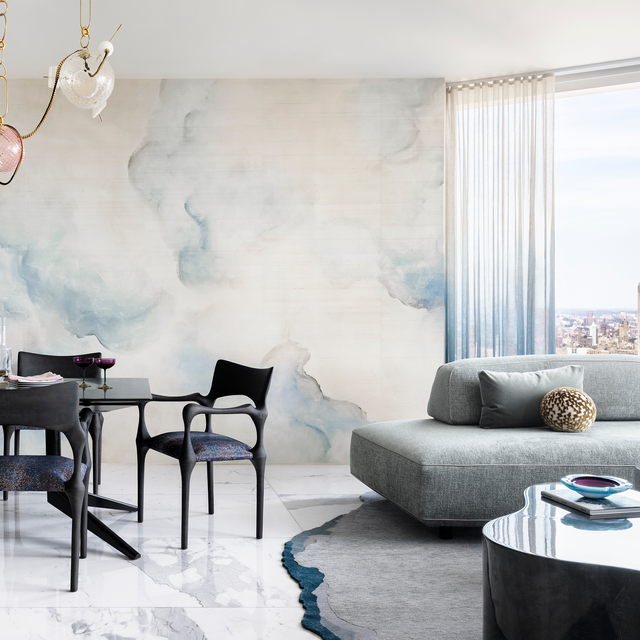 Open-plan NYC dining and living area with Flex modular sofa, marble flooring, and abstract wall mural, designed by Peti Lau.