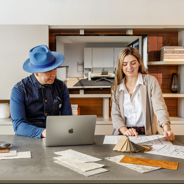 Two people working together during a design consultation with a laptop and fabrics and finishes.