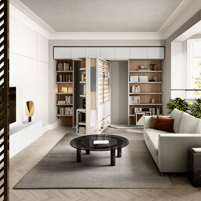 LGM Murphy wall bed (Resource Furniture) partially folded in a modern living room, showing the wooden slatted bed frame and metal folding mechanism between built-in white shelves, beside a sofa and glass coffee table — space-saving multifunctional furniture.