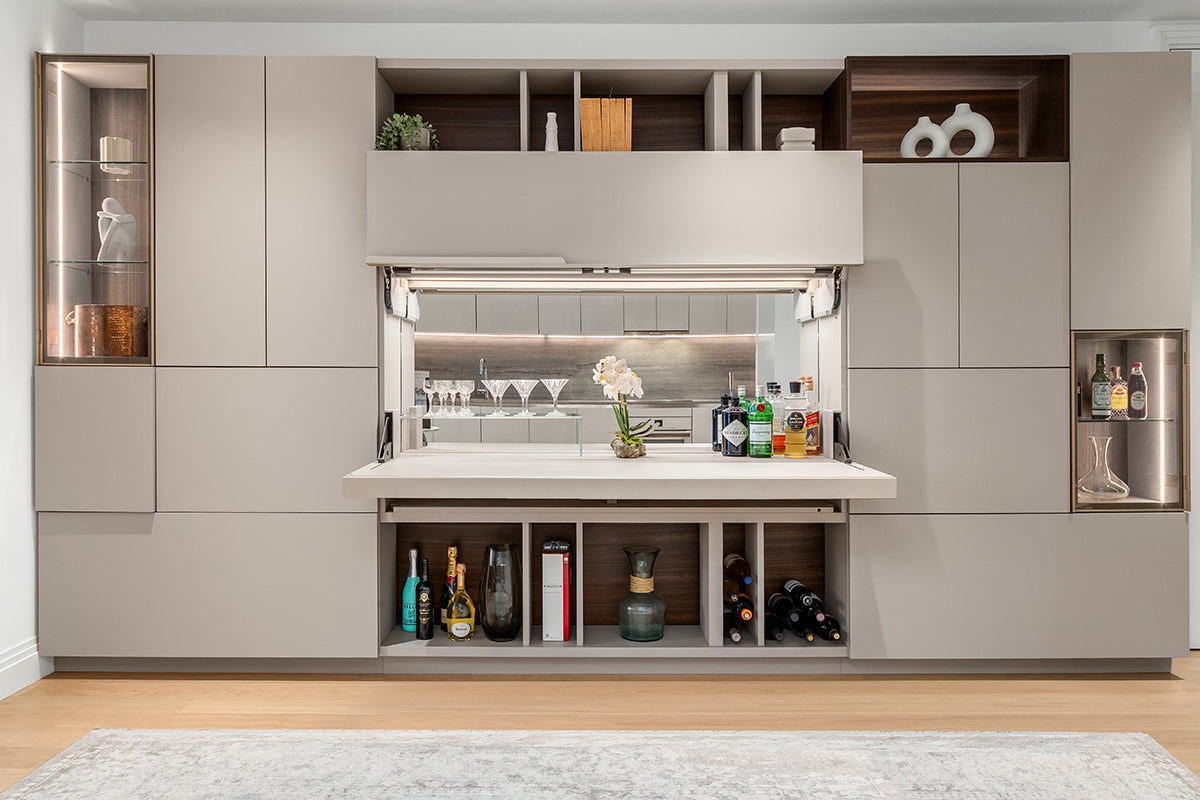 Maxi Bar open within a custom wall system with serving counter, bottle storage, glassware, shelving, and display cabinets.