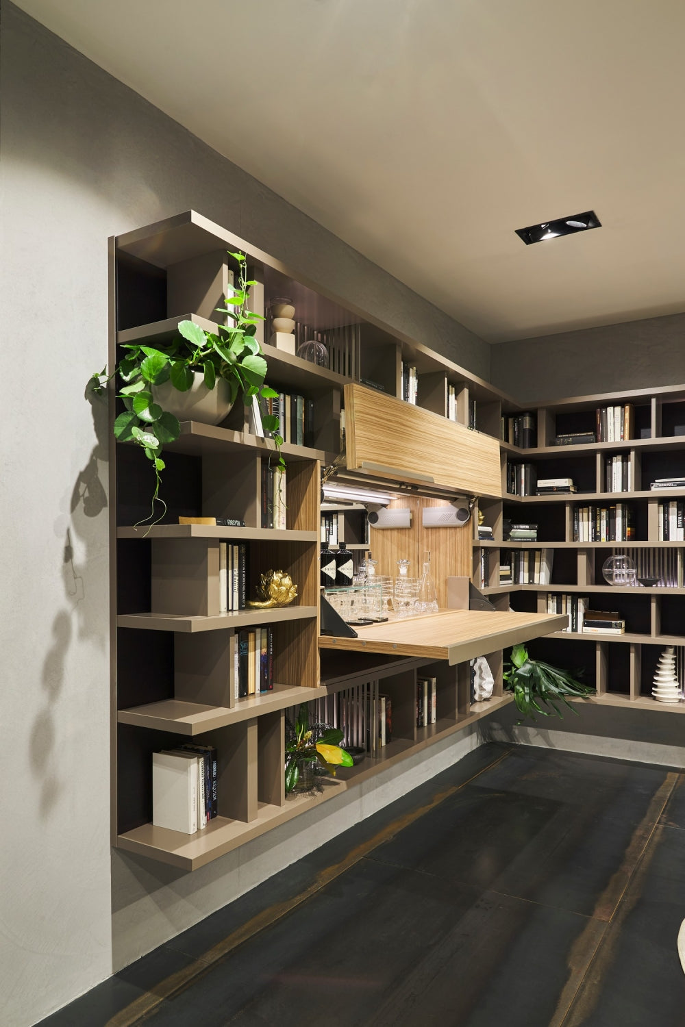 Maxi Bar open within a custom library wall system with bookshelves, wood panels, barware, and integrated lighting.