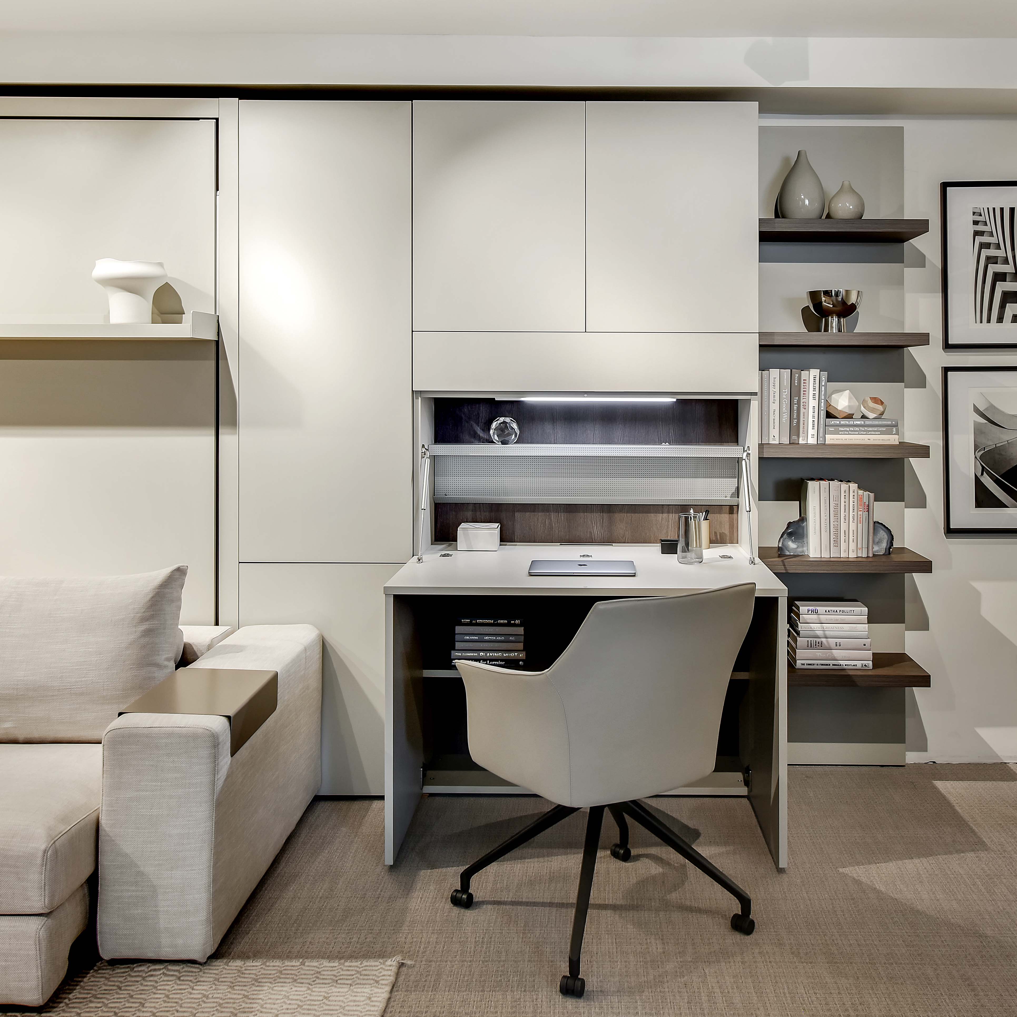 Compact white home office desk with motion-sensor LED lighting, integrated wire management, and soft-close doors, paired with a sectional Murphy bed.